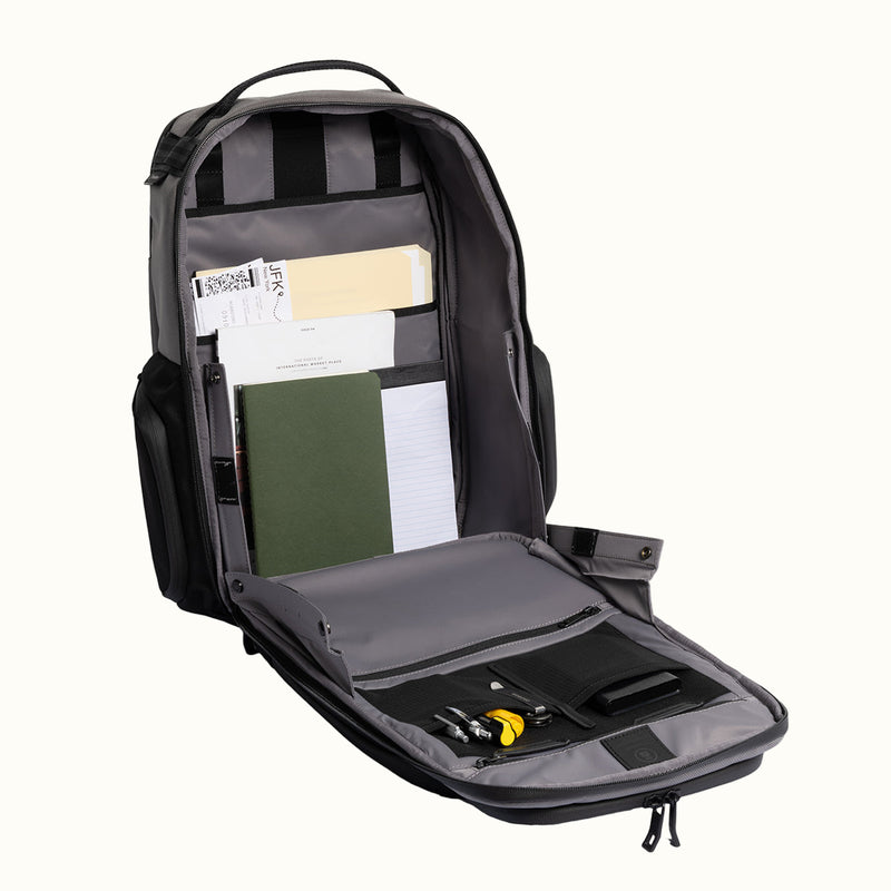 Black backpack with compartments and items on a white background