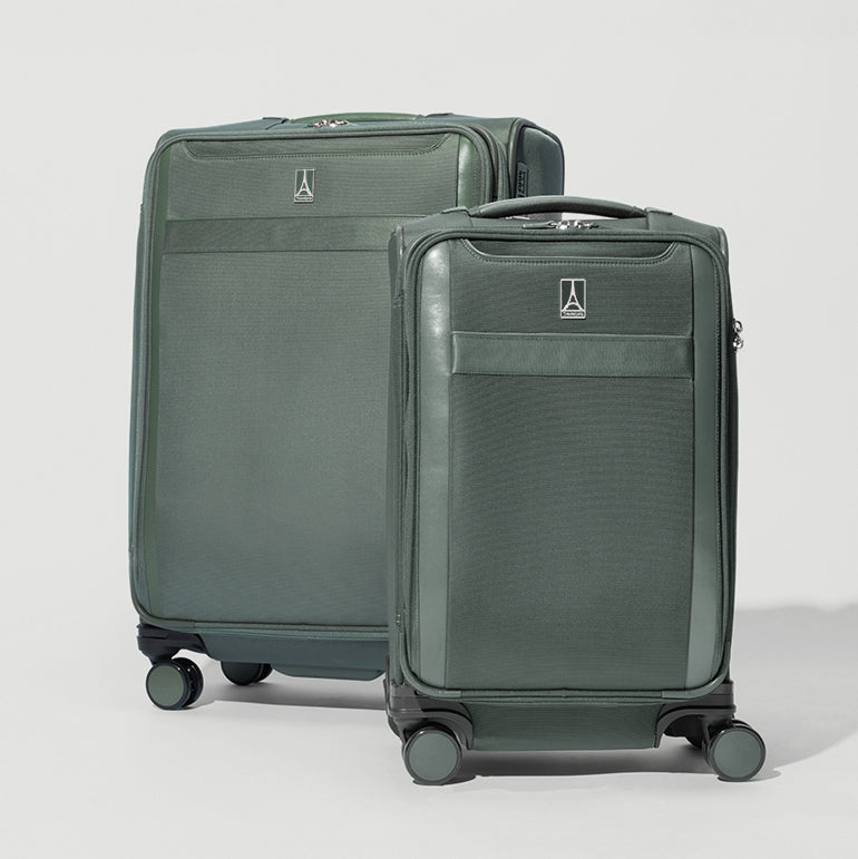 Two green suitcases with wheels on a light gray background