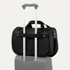 Black tote with a black rear strap over suitcase handle on a white background