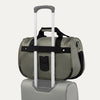 green tote with a black rear strap over suitcase handle on a white background