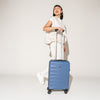 Person walking with the Travelpro Maxlite Air Carry-On Hardside Spinner in Ensign Blue, highlighting lightweight maneuverability.