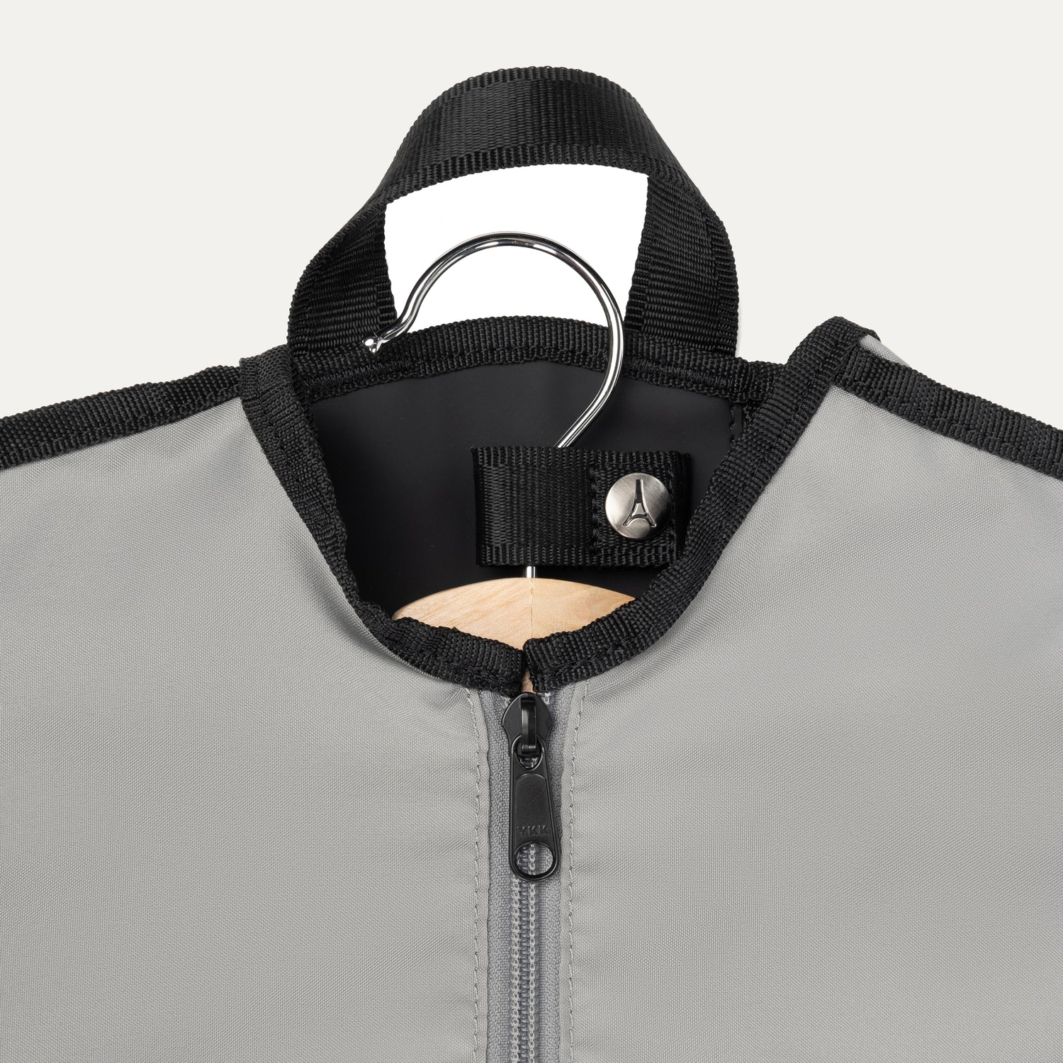 Close-up view of the Travelpro® Essentials™ Drop-in Garment Sleeve, showing the top section with a garment hanger secured by a reinforced snap-tab closure and a durable zipper