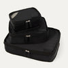 A set of three black Travelpro packing cubes, with the largest at the bottom, medium in the middle, and the smallest at the top, all with zipper closures.