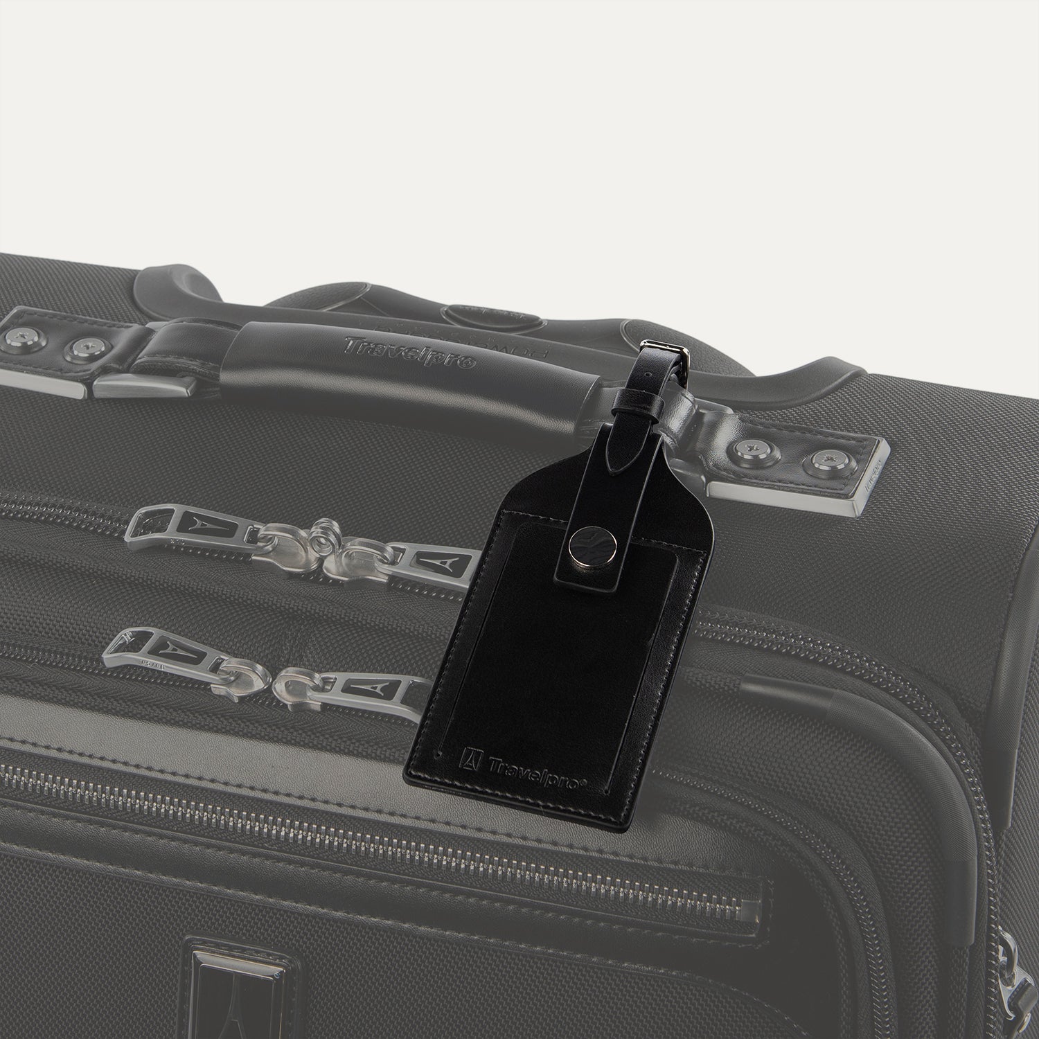 Travelpro Essentials Leather Luggage Tag in Black, attached to suitcase handle with secure buckle strap.