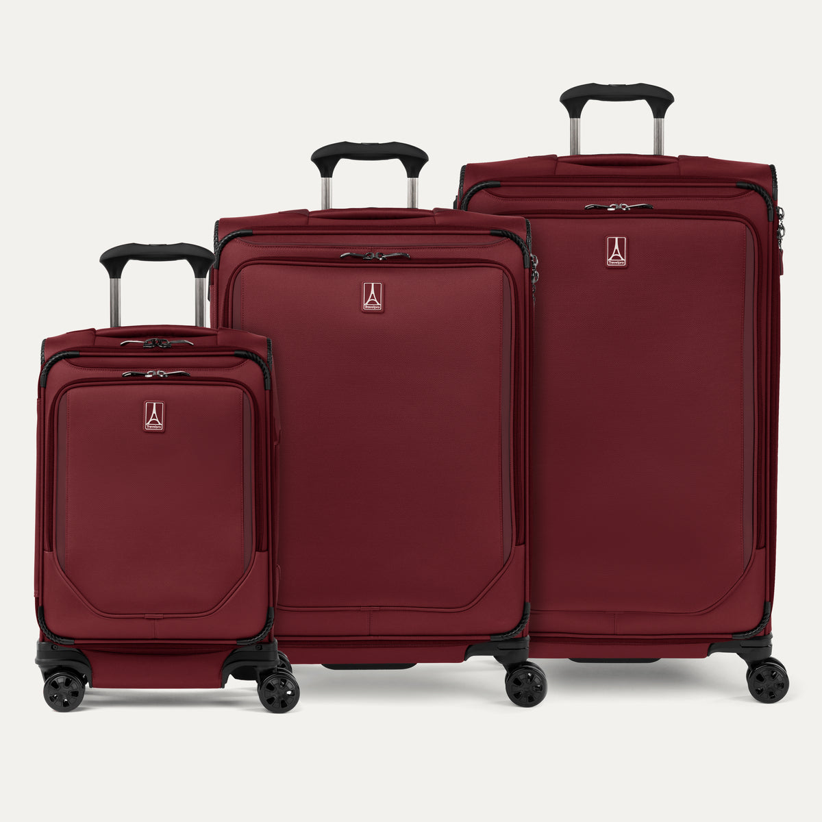 A set of three rosewood red softside spinner suitcases, including a carry-on, medium, and large sizes, aligned in a row with telescopic handles extended.