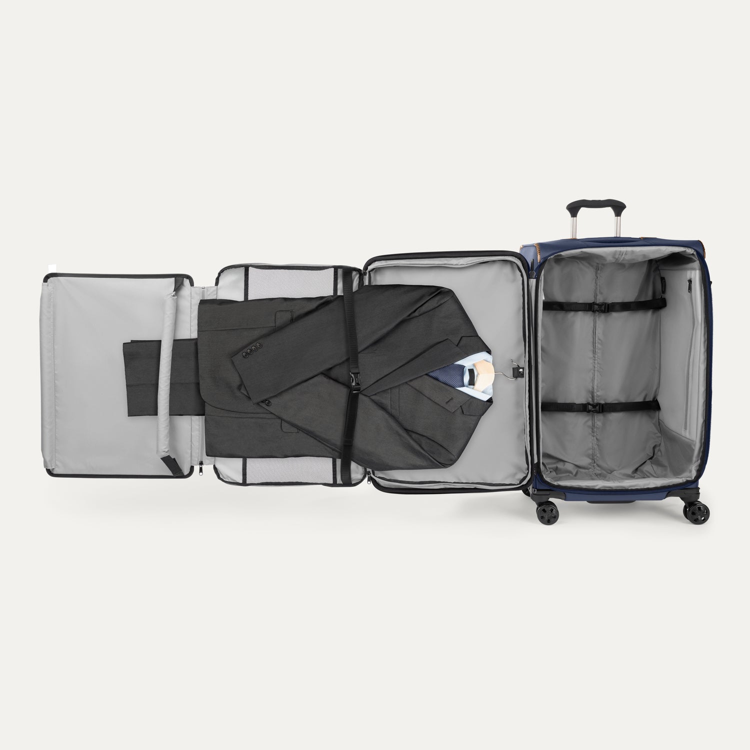 Open suitcase with suit displayed in fold out suiter compartment on white background
