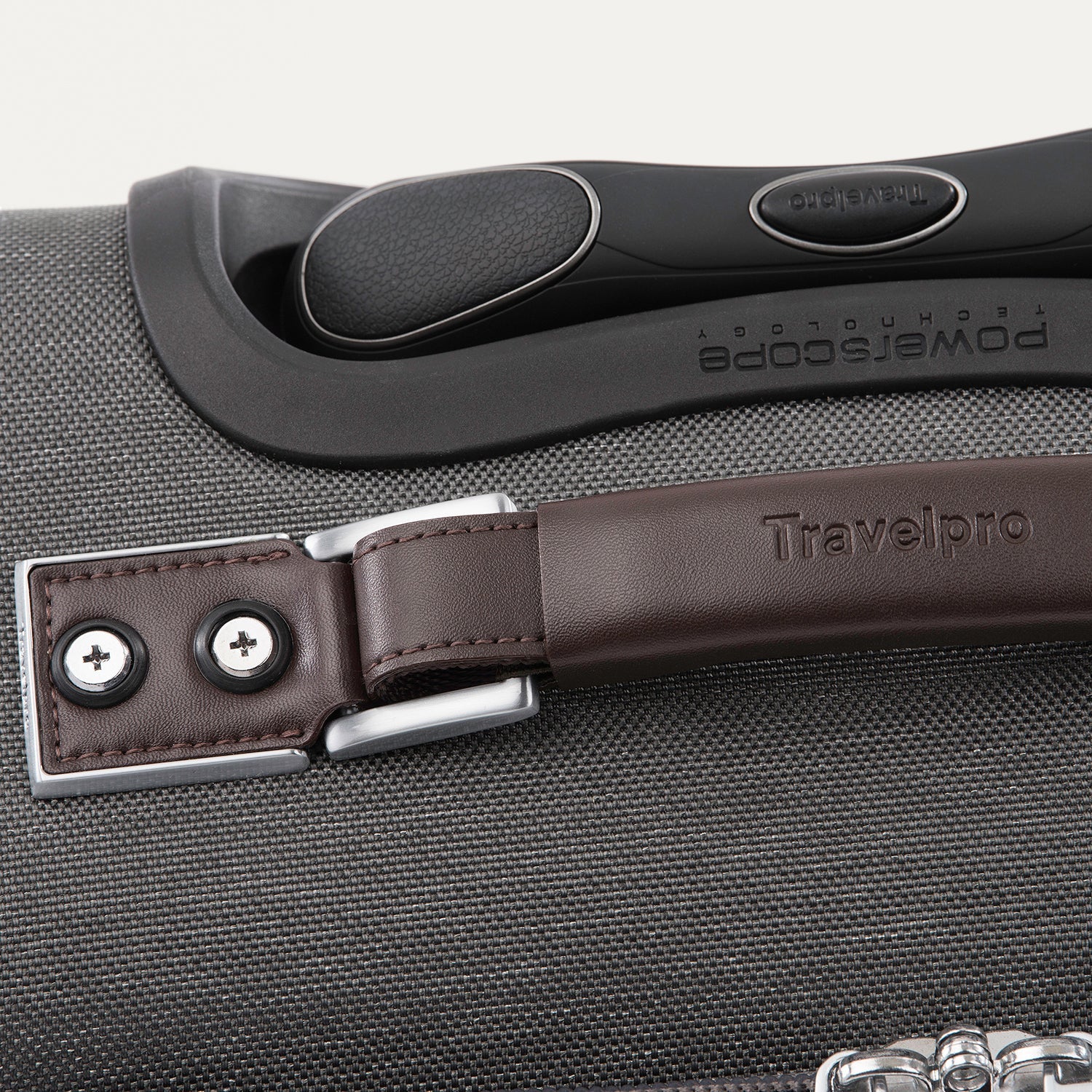 Close-up of a suitcase handle and latch on a gray suitcase.