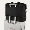 Black weekender with a black rear strap over suitcase handle on a white background