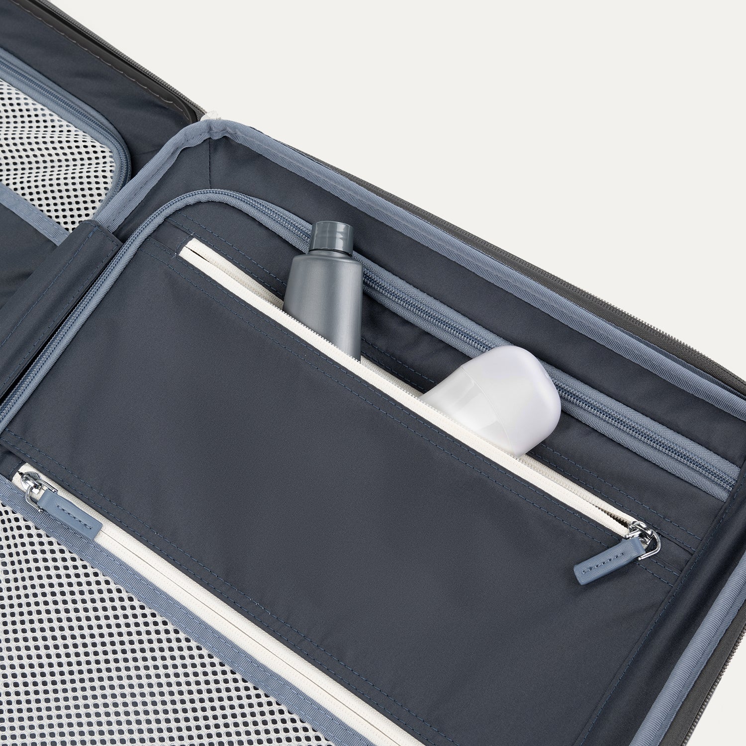 Interior view of Travelpro Platinum Elite Compact Hardside Spinner in Vintage Grey, showing zippered pocket with visible travel-size toiletries.