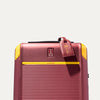 Top front detail of Travelpro x Surgeon carry on Spinner in Daring Red, featuring yellow trim, co-branded logo, and signature luggage tag.