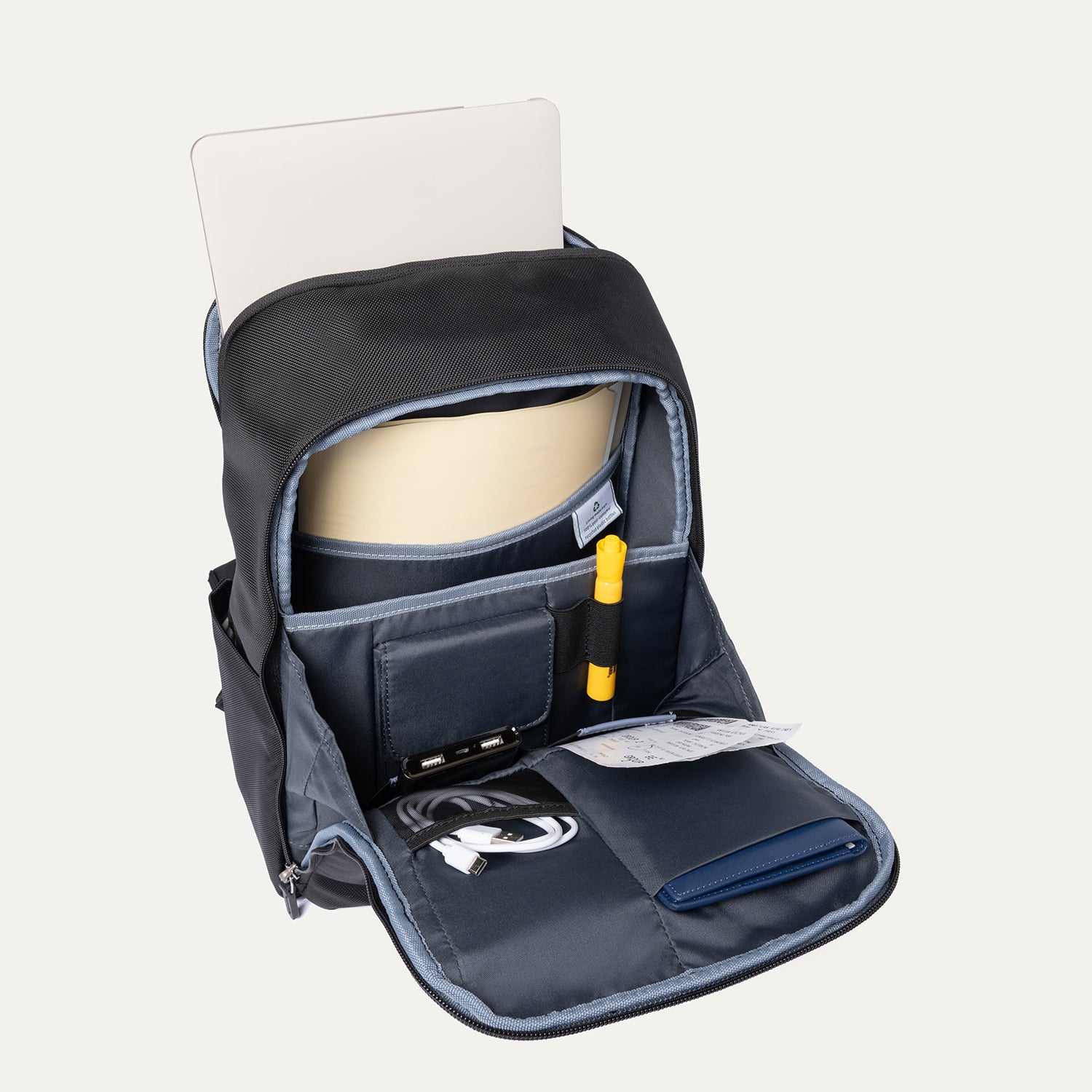 Backpack open with documents, charger, passport and laptop.