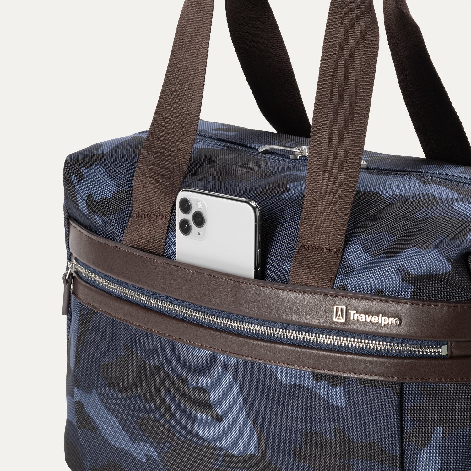 Camouflage travel tote with brown handles and shoulder strap, featuring a laptop partially tucked into the exterior zip pocket.