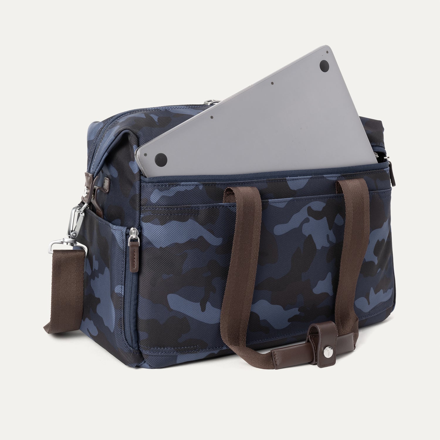 Camouflage travel tote with brown handles and shoulder strap, featuring a laptop partially tucked into the exterior zip pocket.