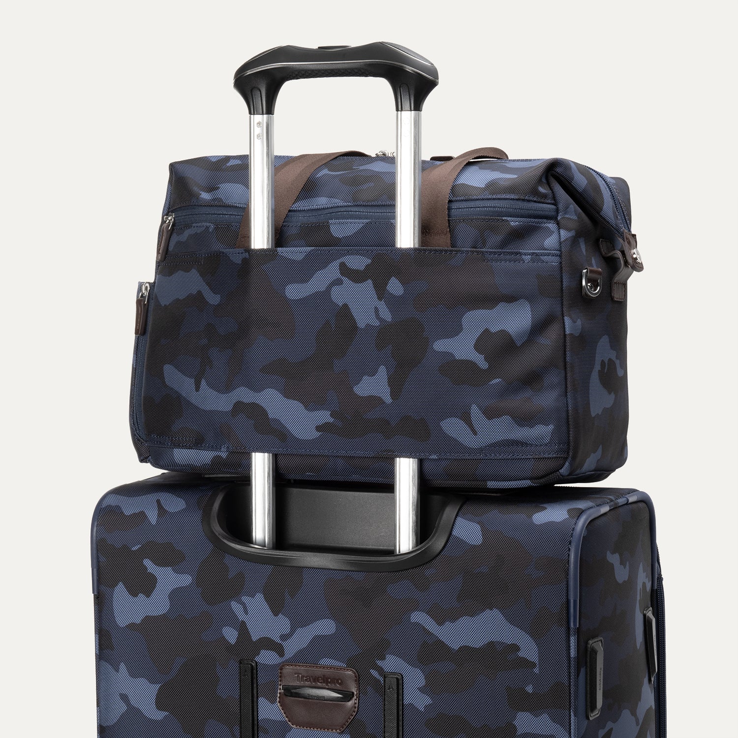 Camouflage travel tote secured over the telescopic handle of a matching rolling suitcase.