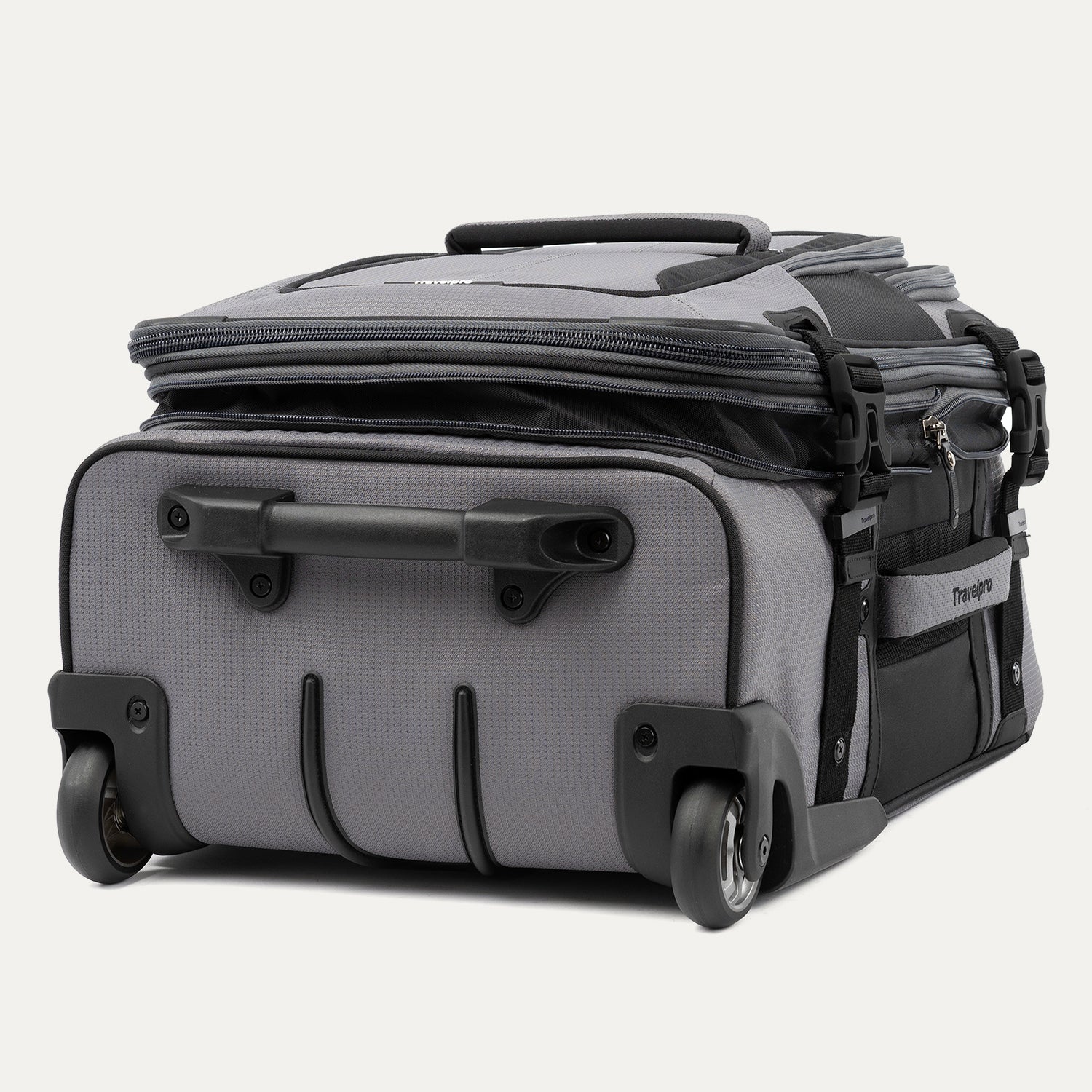 bottom view of the Travelpro® BOLD™ by Travelpro® carry-on in Gray Black, showcasing its sturdy inline wheels, reinforced bottom handle, and rugged protective base