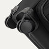 Close-up of Travelpro Versapack Spinner in Black, highlighting the Magnetically Self-Aligning Wheels for smooth mobility.