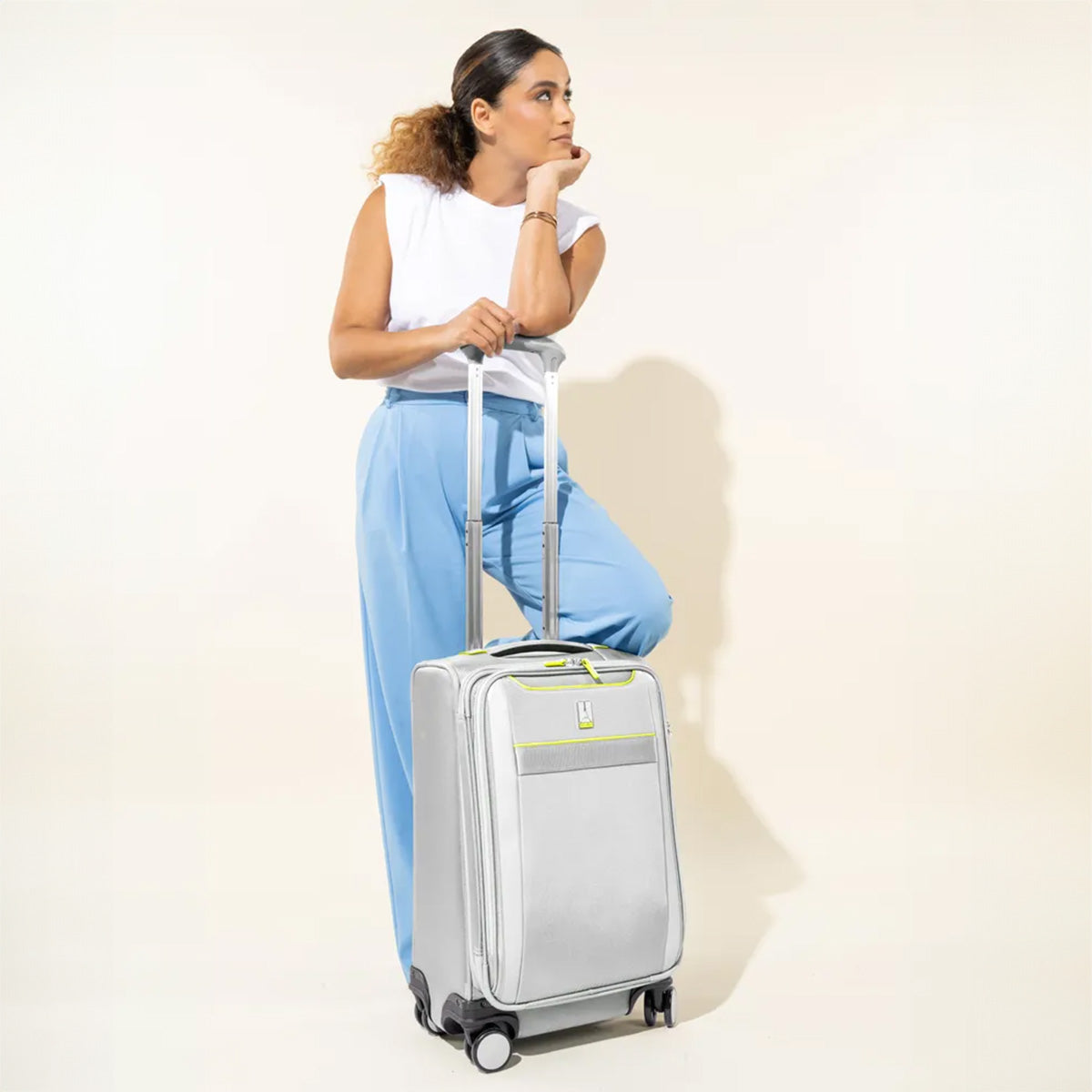 Front view of VersaPack®+ Carry-on Expandable Spinner in Cyber Lime, shown with a 5'7" model for scale, featuring extended handle and four-wheel spinner design