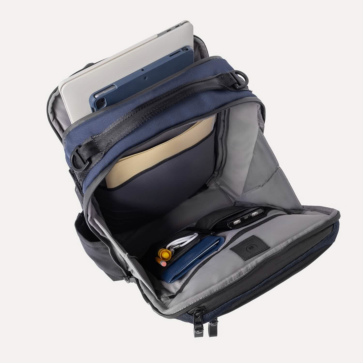 Open backpack with compartments and a tablet inside on a white background