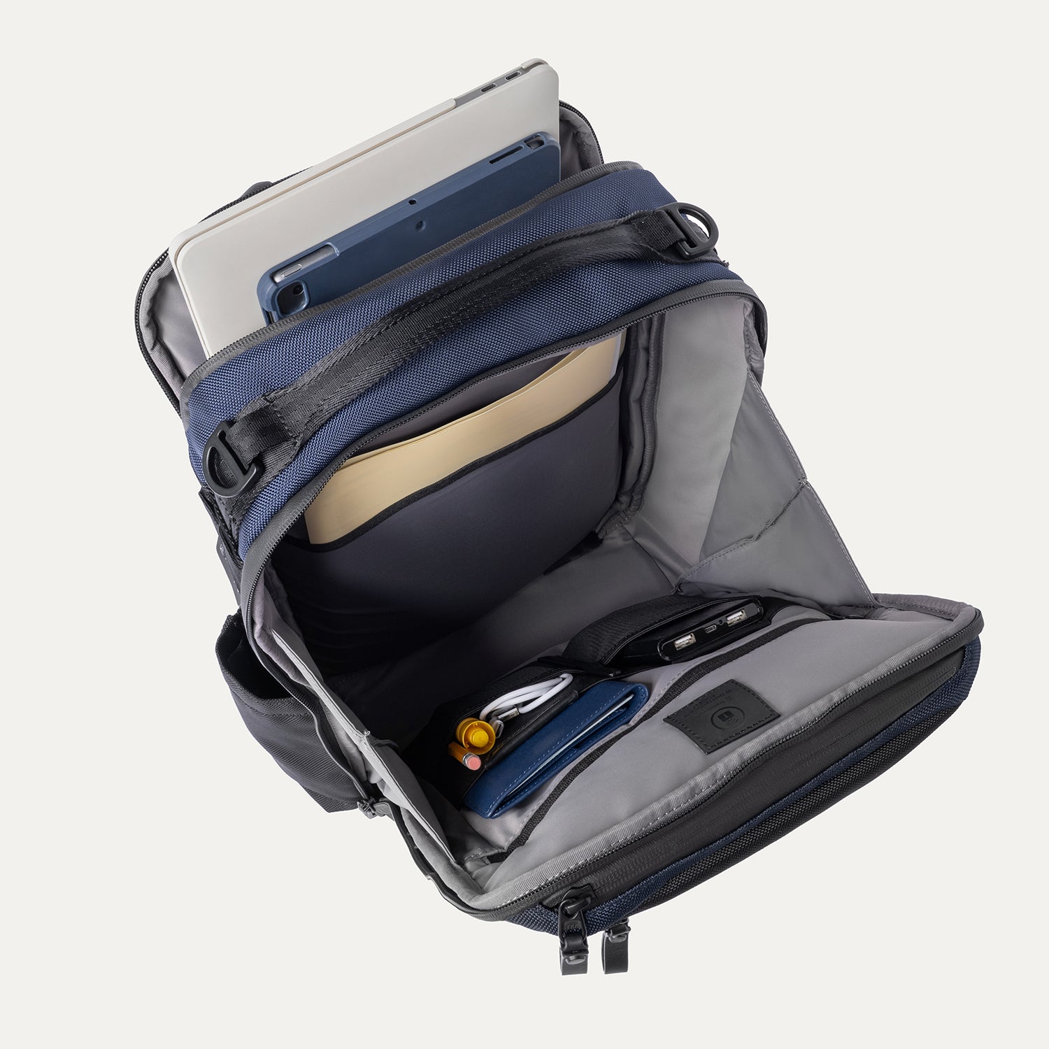 Open backpack with compartments and a tablet inside on a white background