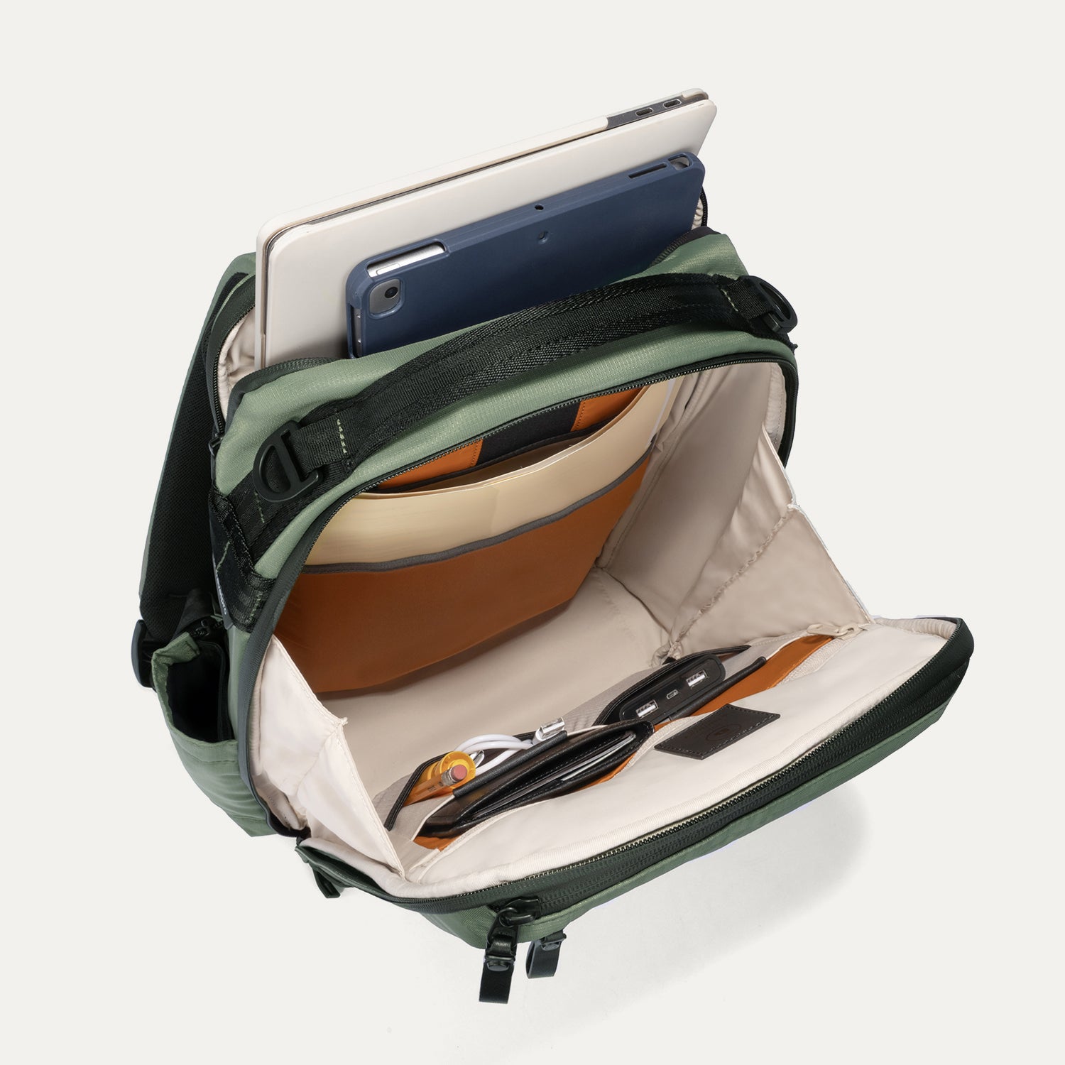 Green backpack with compartments containing electronic devices on a white background