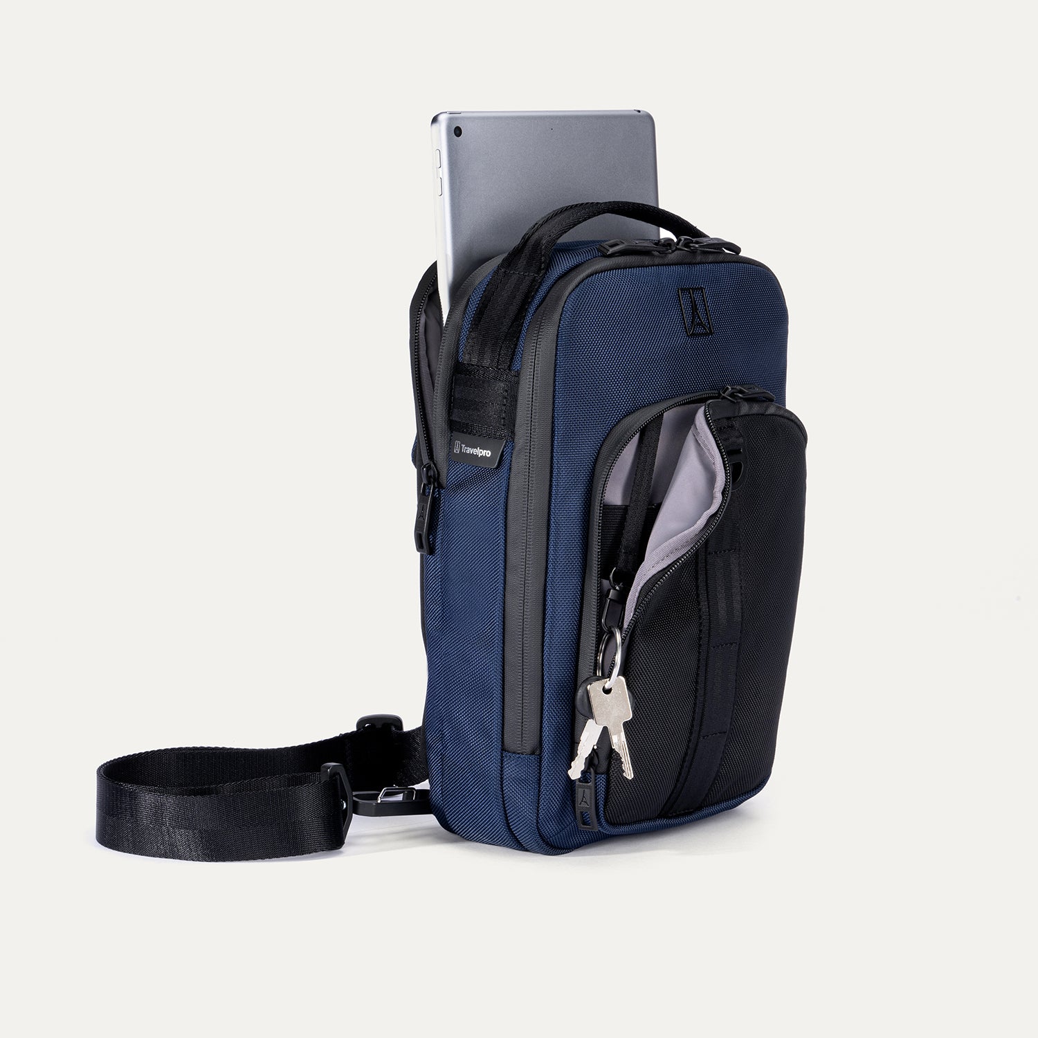 Travelpro Altitude Crossbody 6L in Aviator Navy, with tablet in rear sleeve and keys clipped inside front pocket.