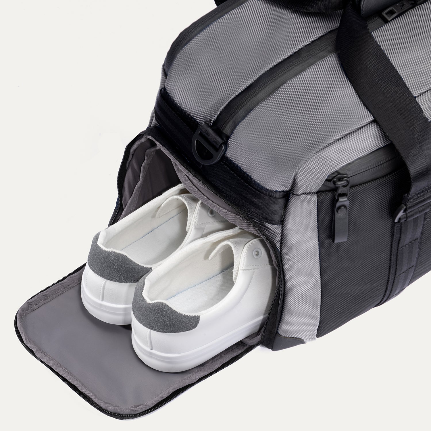 Travelpro Altitude Day-to-Day Duffel in Falcon Grey, with shoe compartment open and sneakers neatly stowed inside.