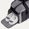 Travelpro Altitude Day-to-Day Duffel in Falcon Grey, with shoe compartment open and sneakers neatly stowed inside.