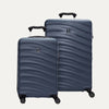 A set of two blue hardside spinner suitcases, one carry-on size and one medium check-in size, with a textured surface, integrated handles, and wheels.