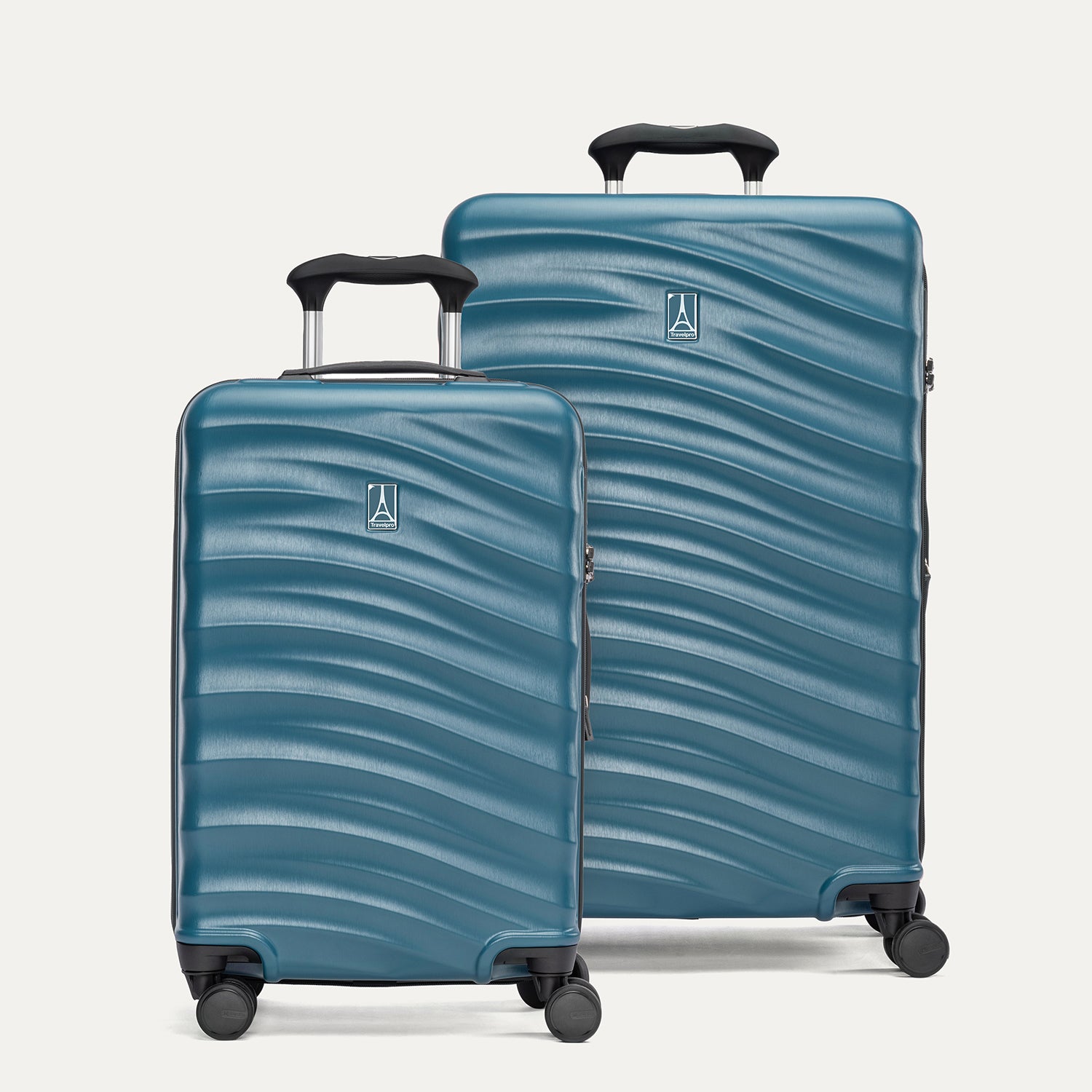 A set of two blue hardside spinner suitcases, one carry-on size and one medium check-in size, with a textured surface, integrated handles, and wheels visible.