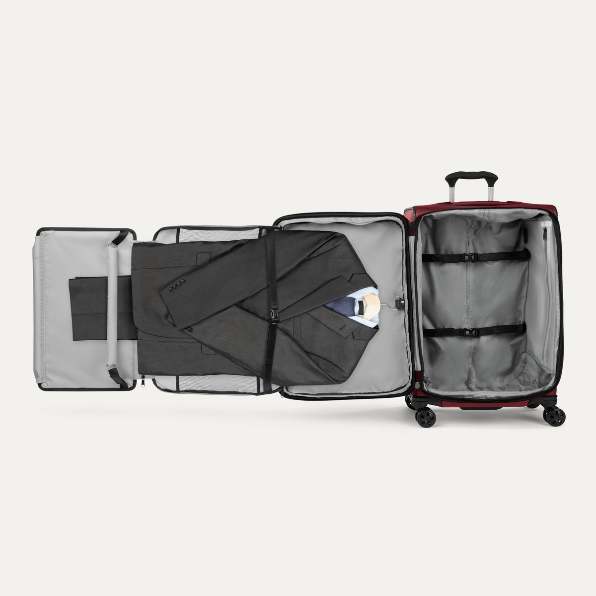 Open suitcase with suit displayed in fold out suiter compartment on white background