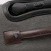 Close-up of a suitcase handle with a brown leather wrap on a gray textured suitcase.