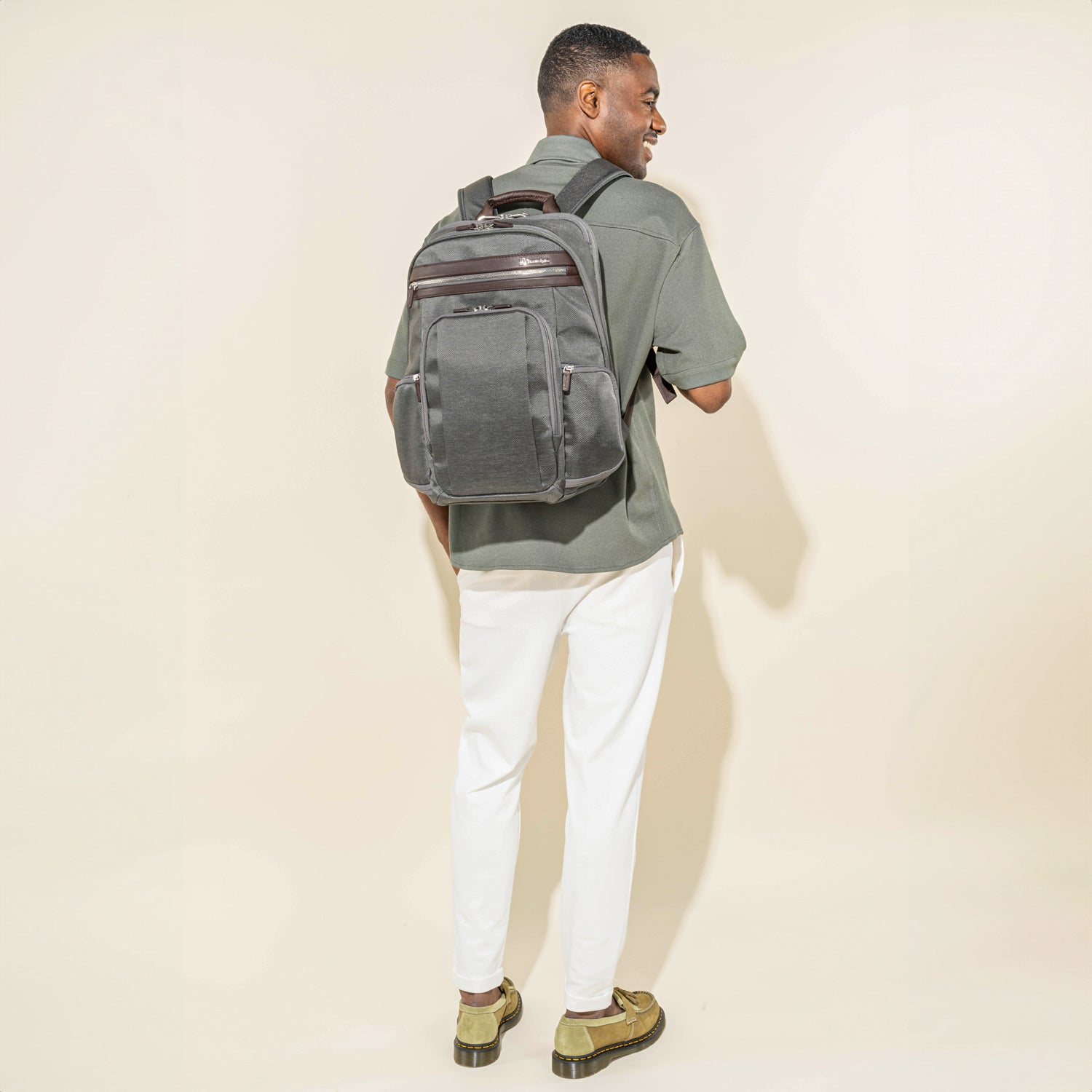 Person wearing a vintage grey backpack on a white background