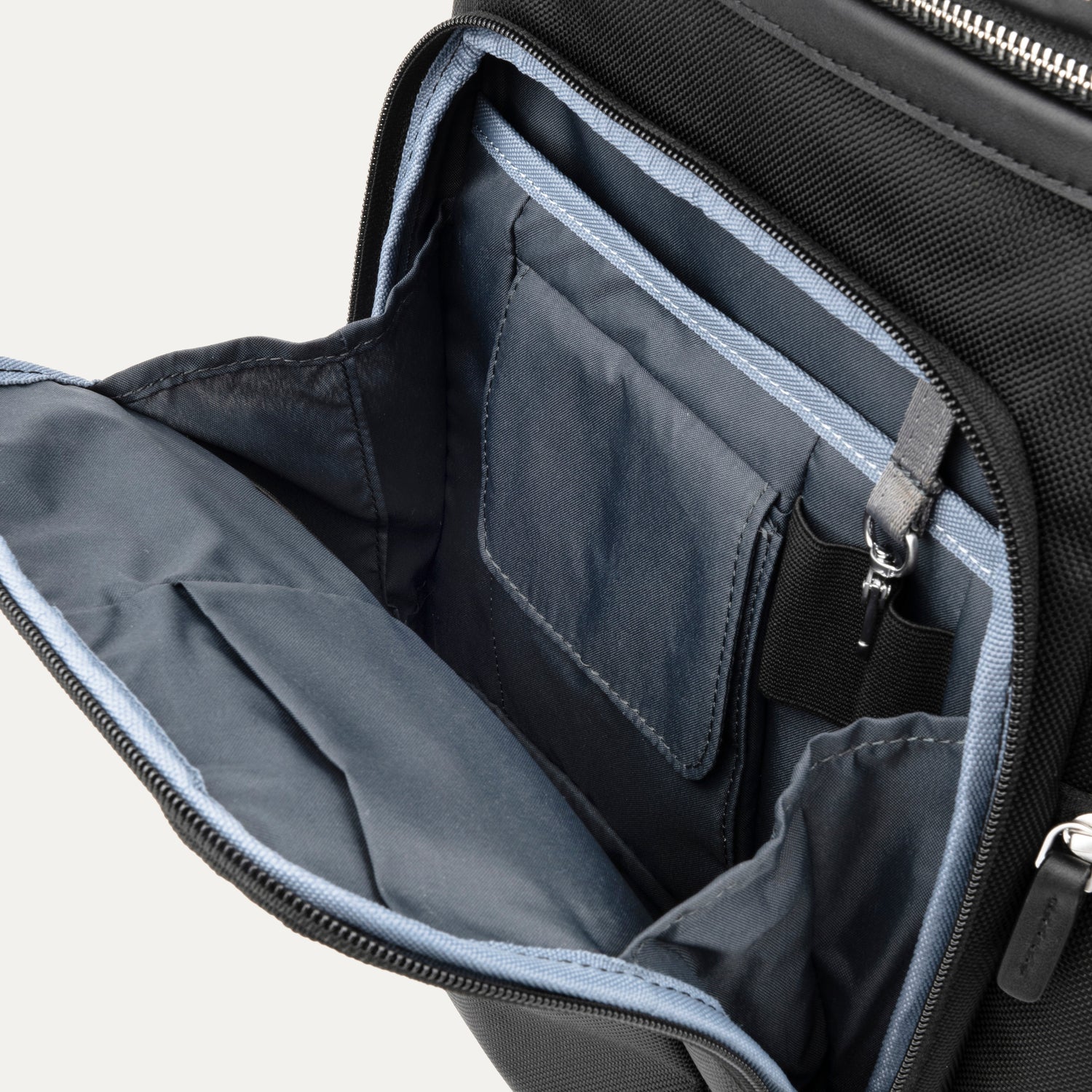Open front compartment of a black backpack on a white background