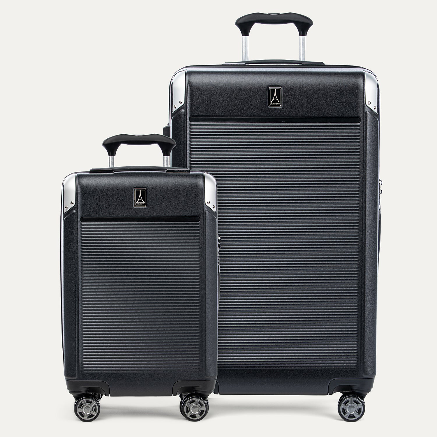 A set of two black hardside spinner suitcases, one carry-on and one check-in size, with textured finish, metallic corners, and wheels.