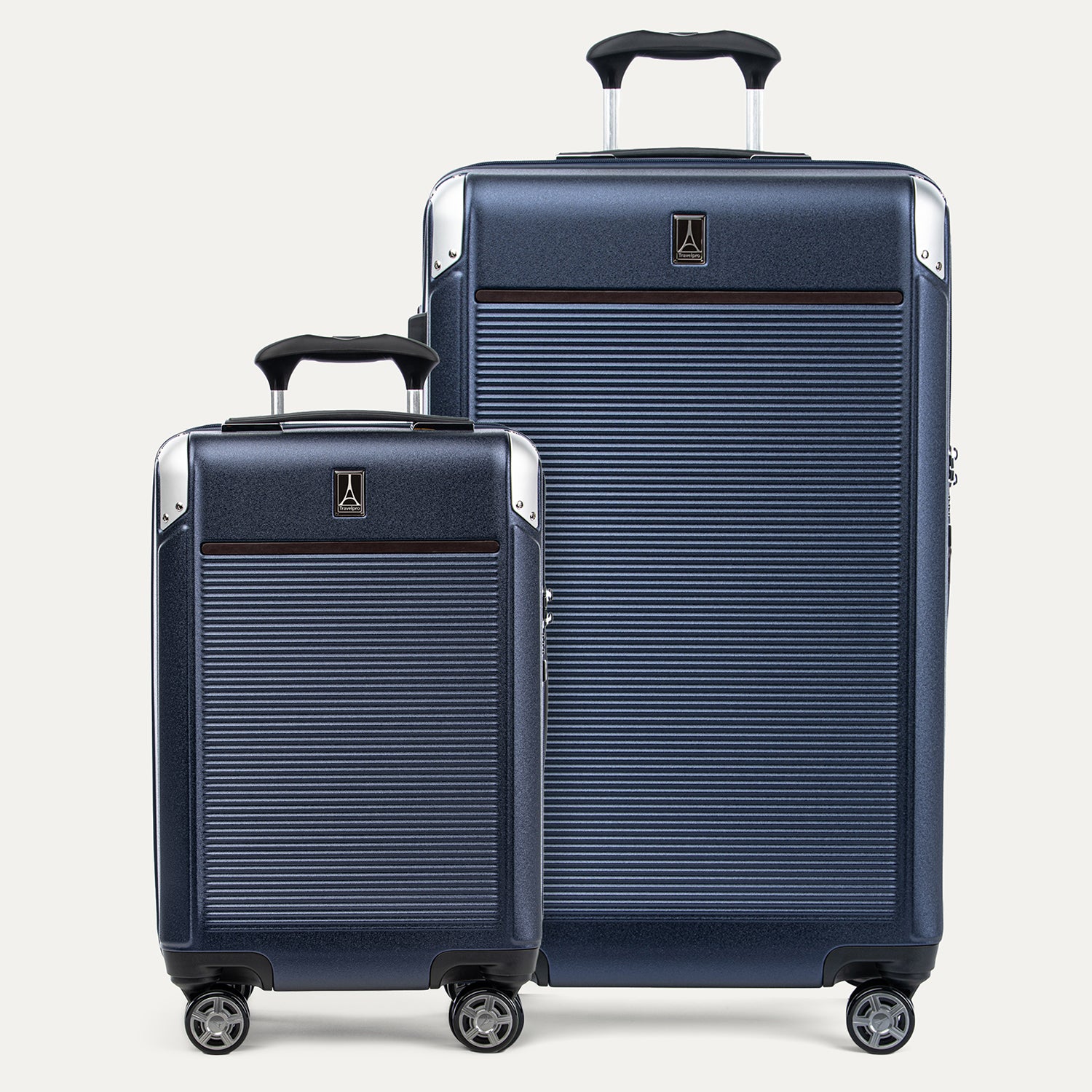 A set of two navy blue hardside spinner suitcases, one carry-on and one check-in size, with textured finish, metallic corners, and wheels.