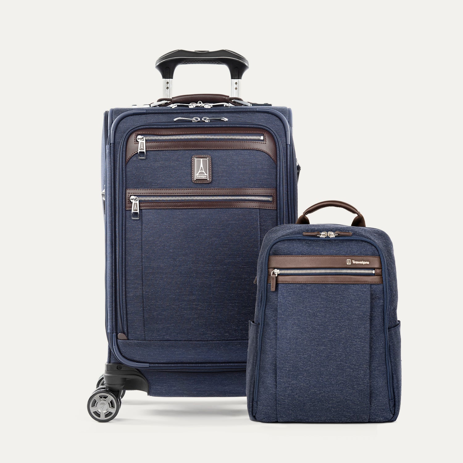 A set of navy blue travel luggage, including an expandable carry-on spinner and a slim backpack, with brown leather accents.