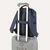 True navy backpack with a rear strap over suitcase handle on a white background