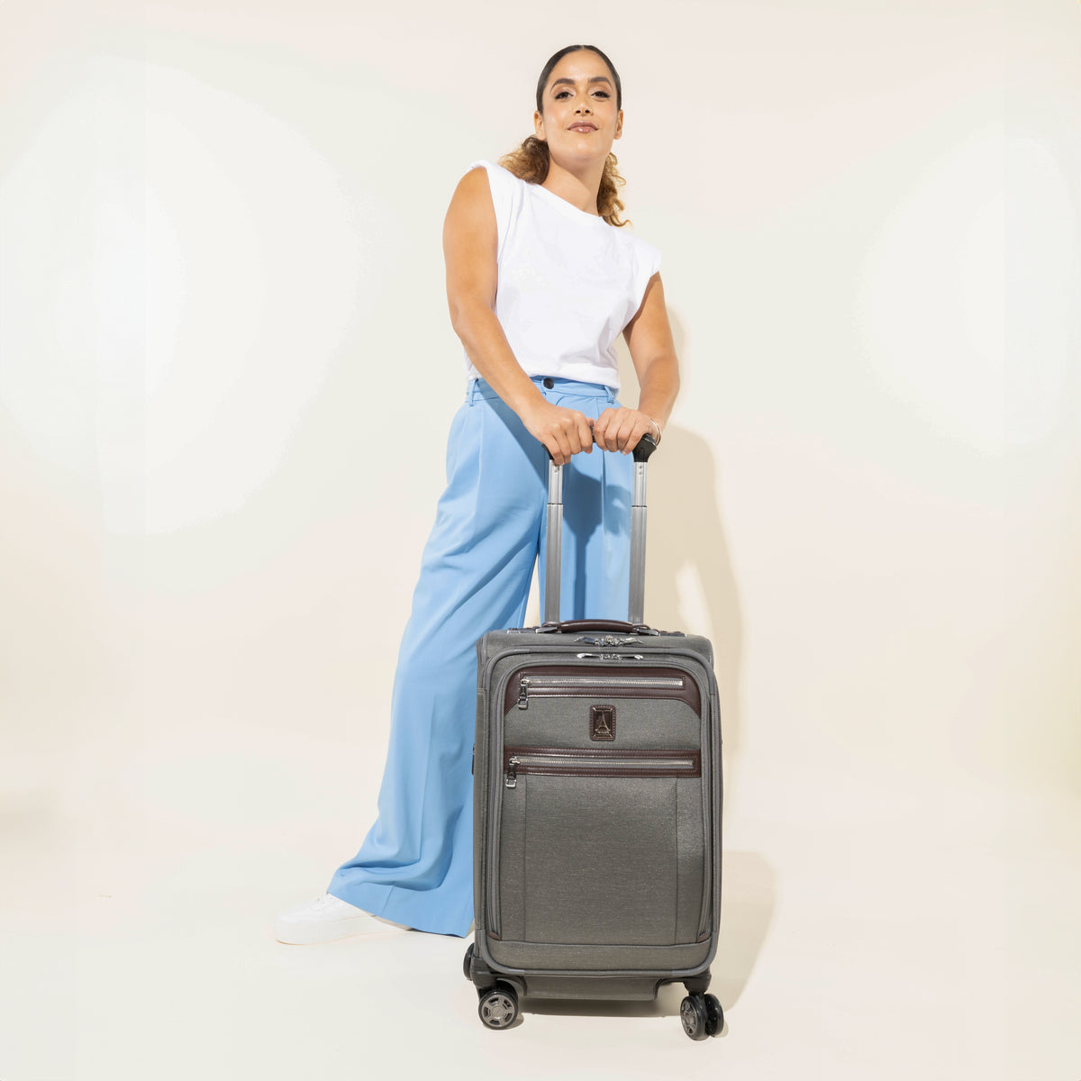 Person holding a vintage grey suitcase on a white background