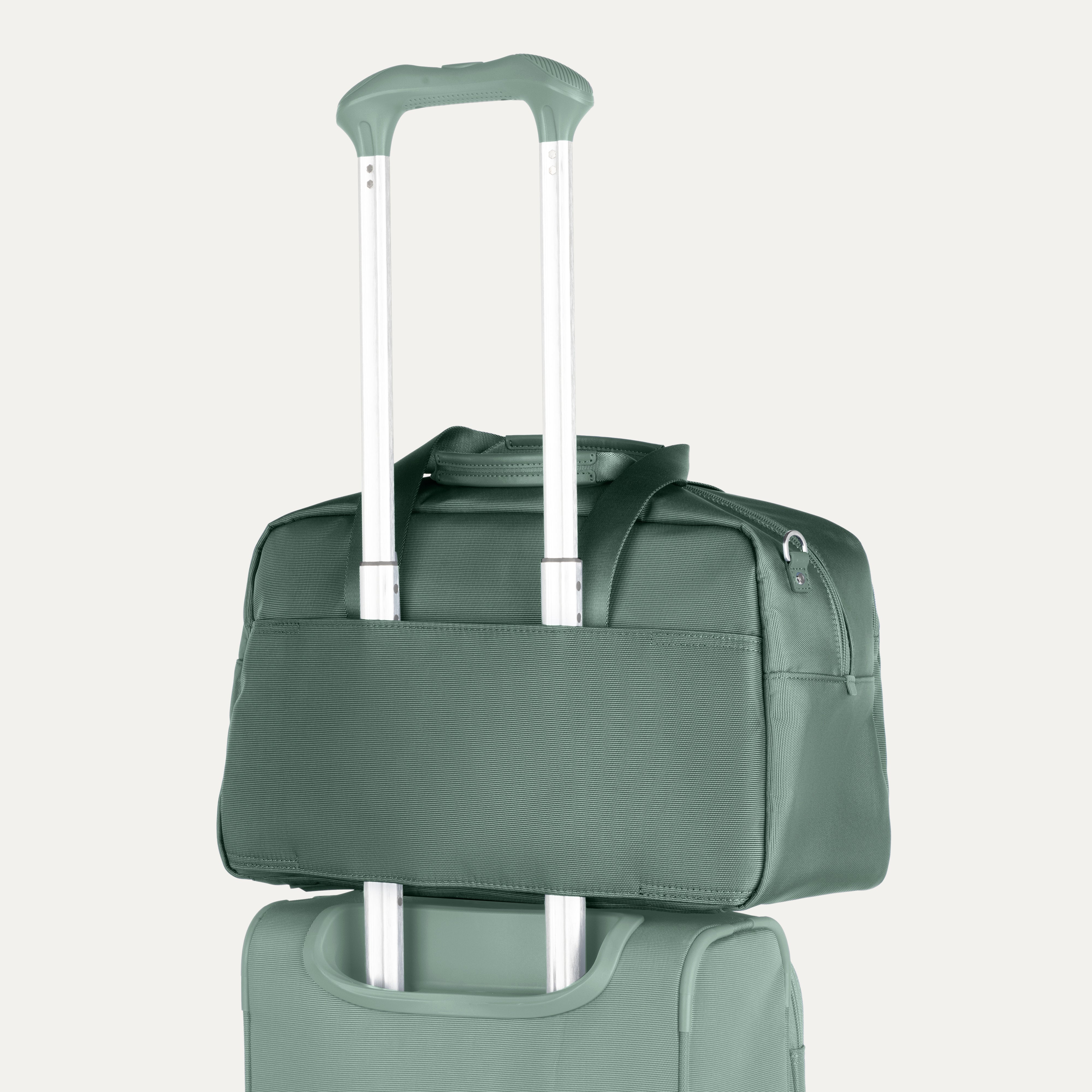 Green rolling suitcase with a tote stacked on top on a white background