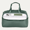 Green travel bag with a white interior pocket showcasing phone and notebook on a light gray background