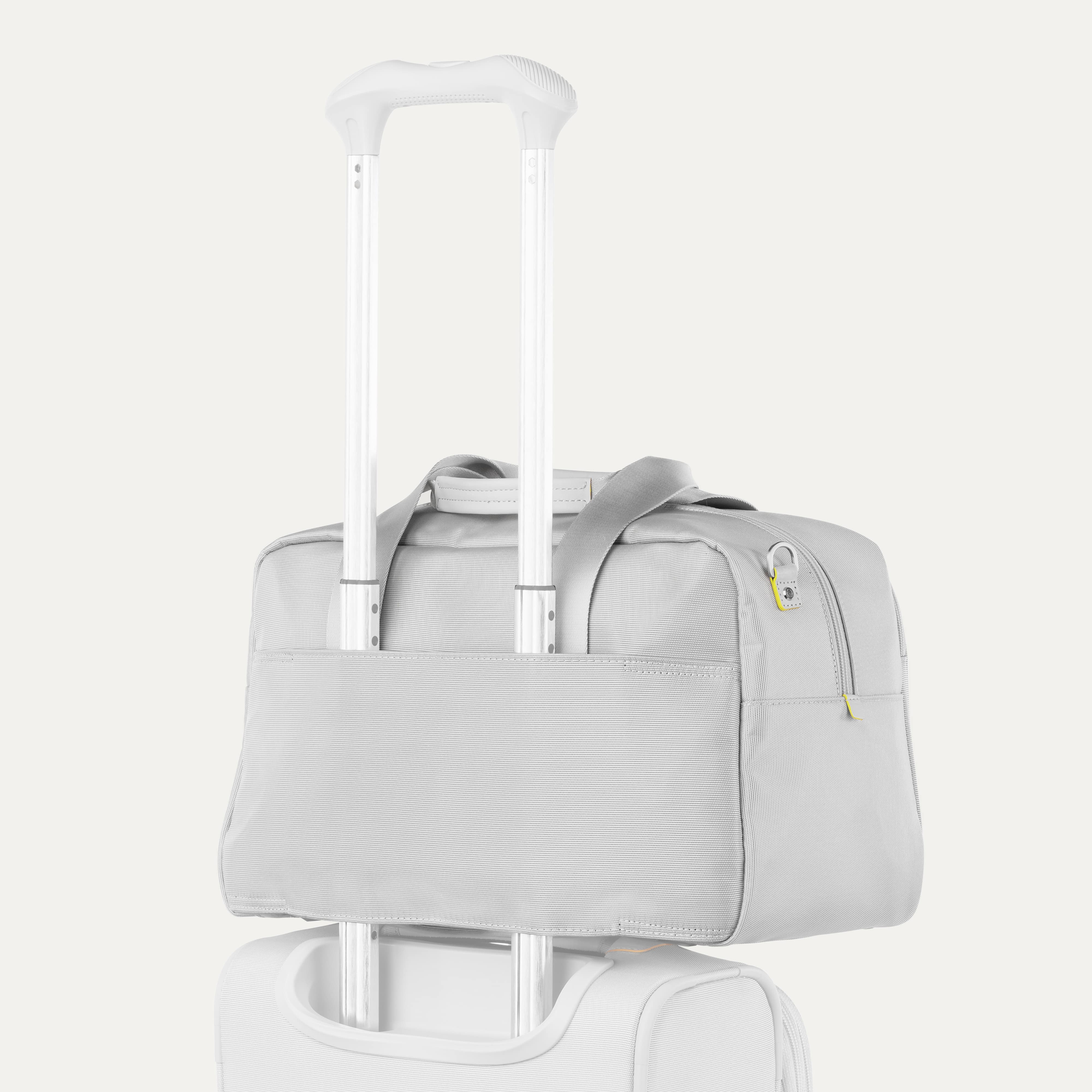 Grey tote bag sittting on top of a grey carry on suitcase