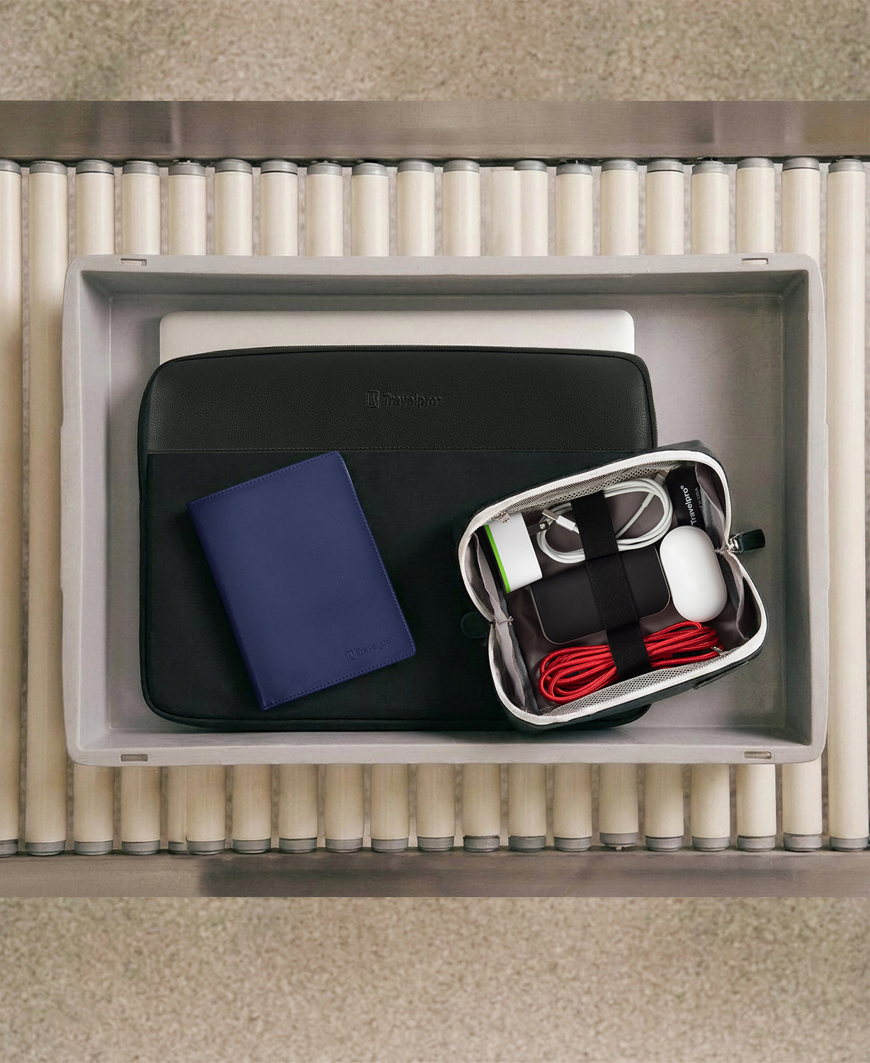 Top view of a drawer with electronic accessories including a black case, blue notebook, and white mouse.