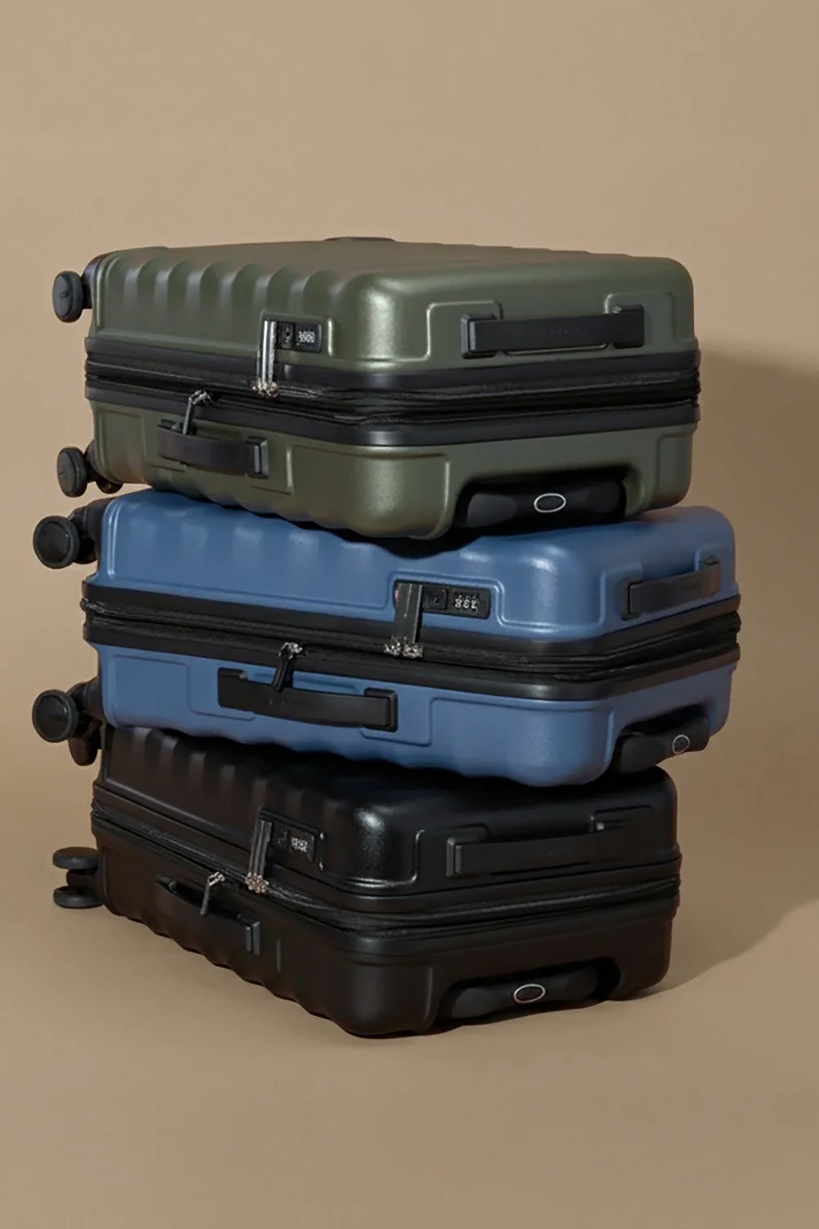 Three suitcases stacked on a beige background