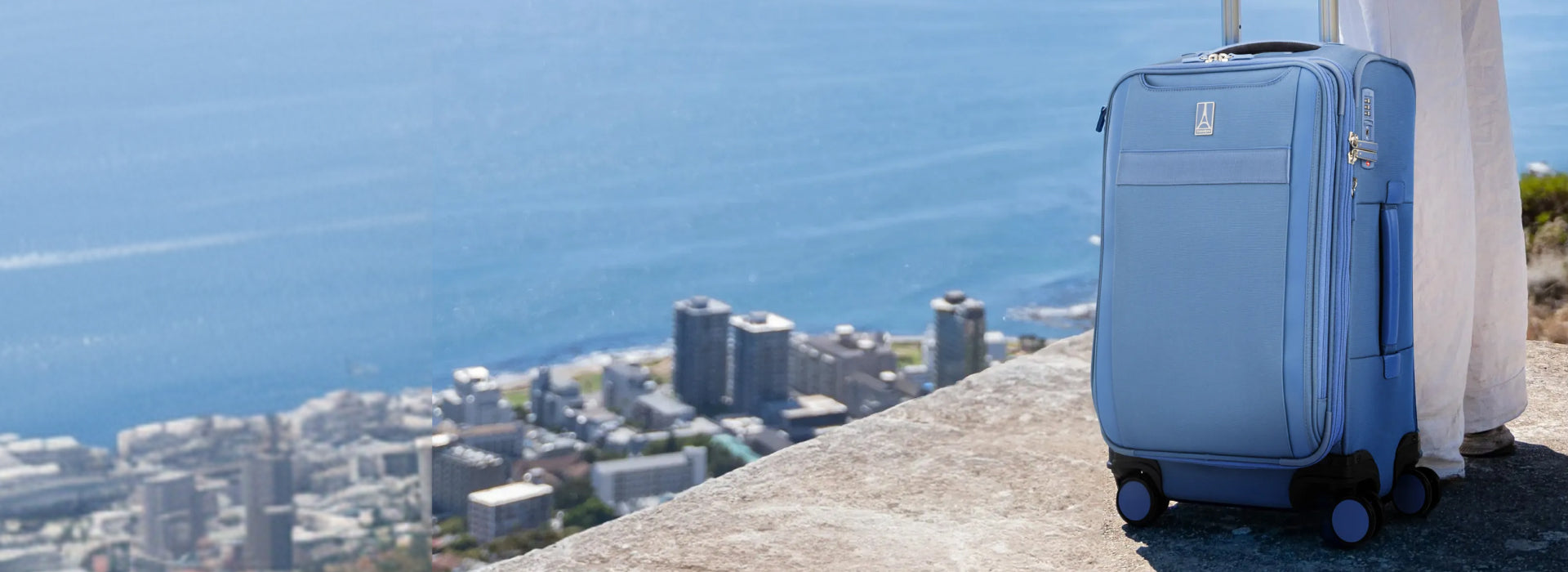 Blue Luggage on a mountain top overlooking the sea