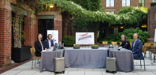 Radio show hosts Robert and Mary Cary hosting with two travelpro platinum elite hardside suitcases being displayed