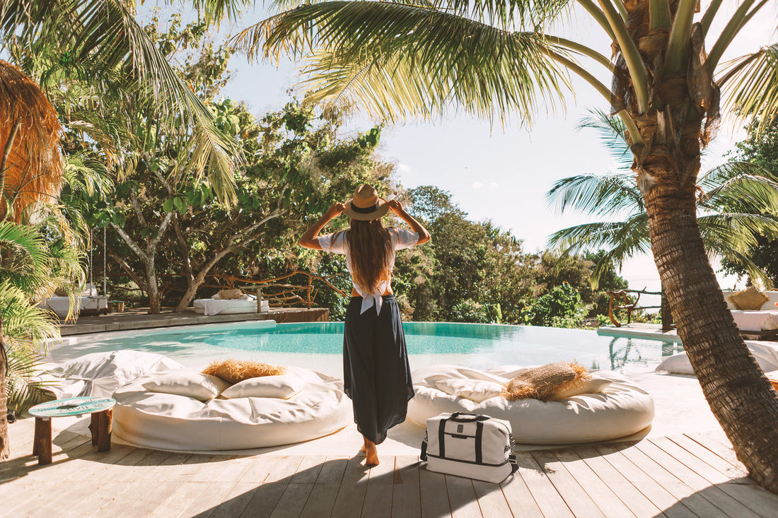 woman at a tropical resort, standing facing the pool 