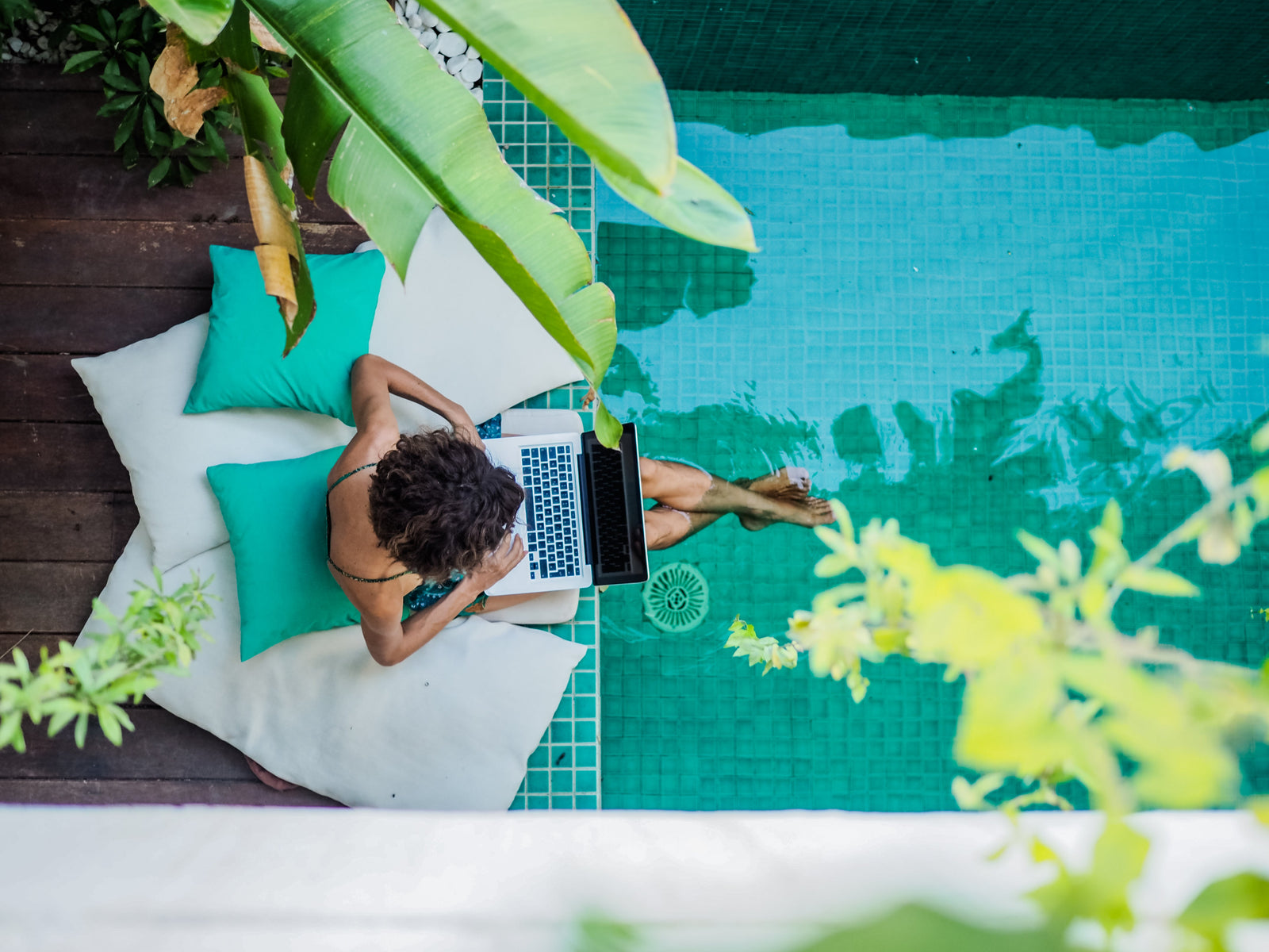 Woman sitting poolside on a laptop
