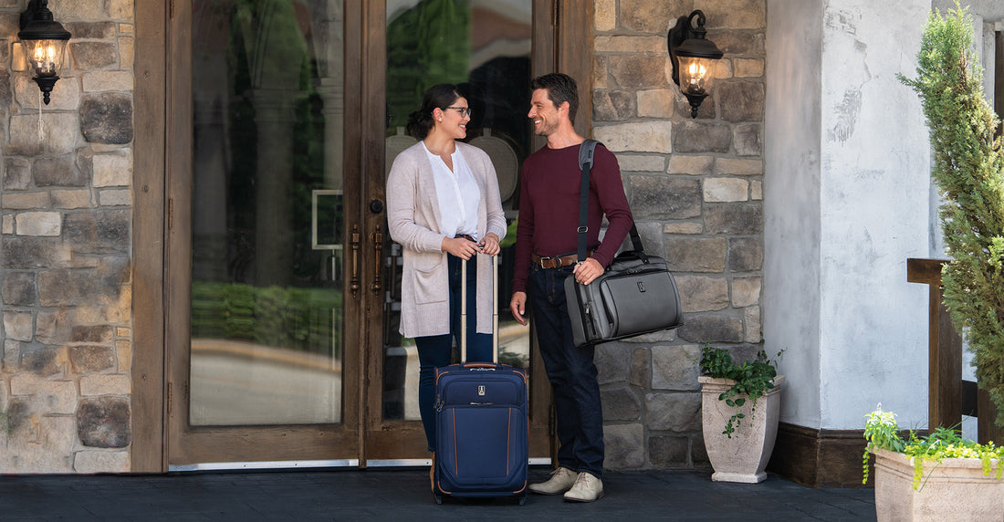 Man and woman carrying Travelpro duffel bag and rolling suitcase