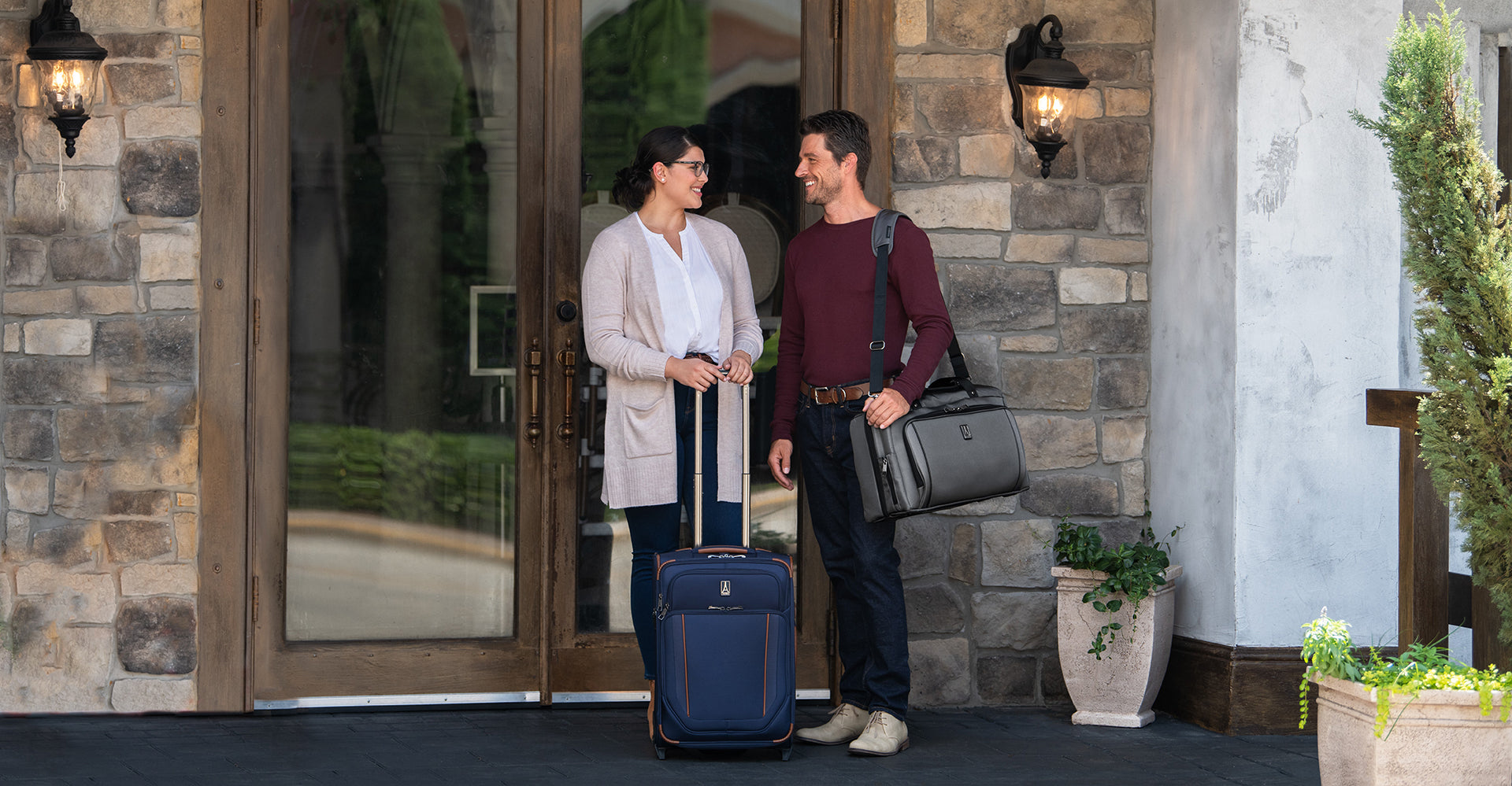 Man and woman carrying Travelpro duffel bag and rolling suitcase