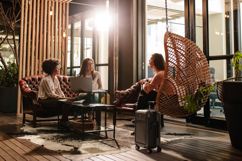Women sitting in hotel lobby working with suitcase next to them